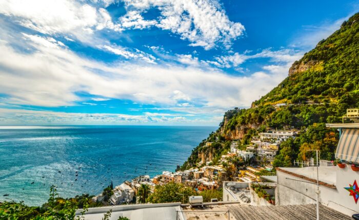 High angle view of Positano colorful houses and steep cliffs under a bright blue sky.