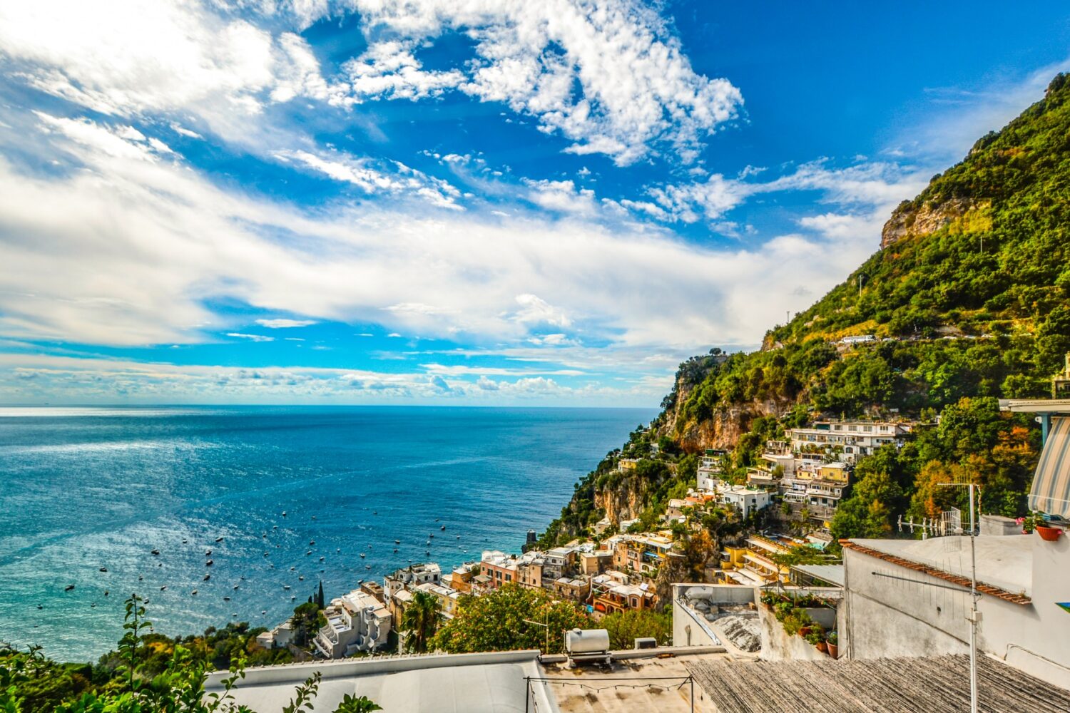 High angle view of Positano colorful houses and steep cliffs under a bright blue sky.