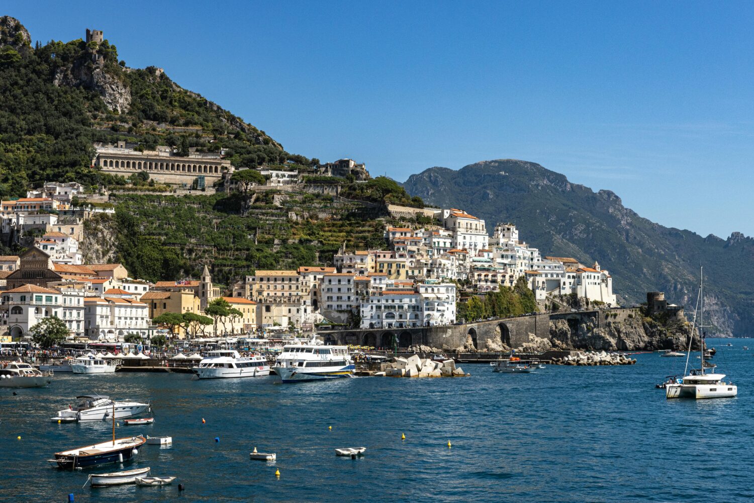 Panoramic view of Amalfi harbor with white houses and blue sea during a day tour